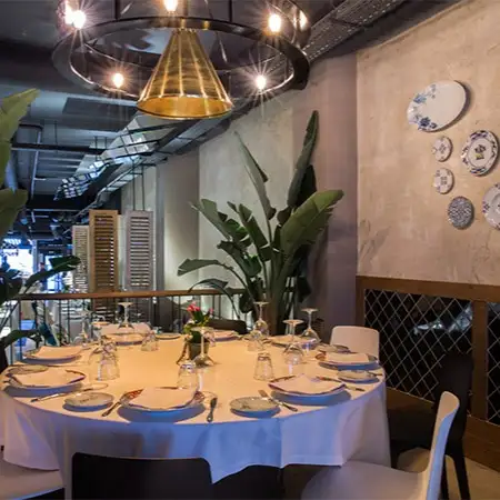 El Barril de las Cortes presenta una mesa redonda elegantemente dispuesta, rodeada de decoración sofisticada y detalles que evocan calidez y estilo.