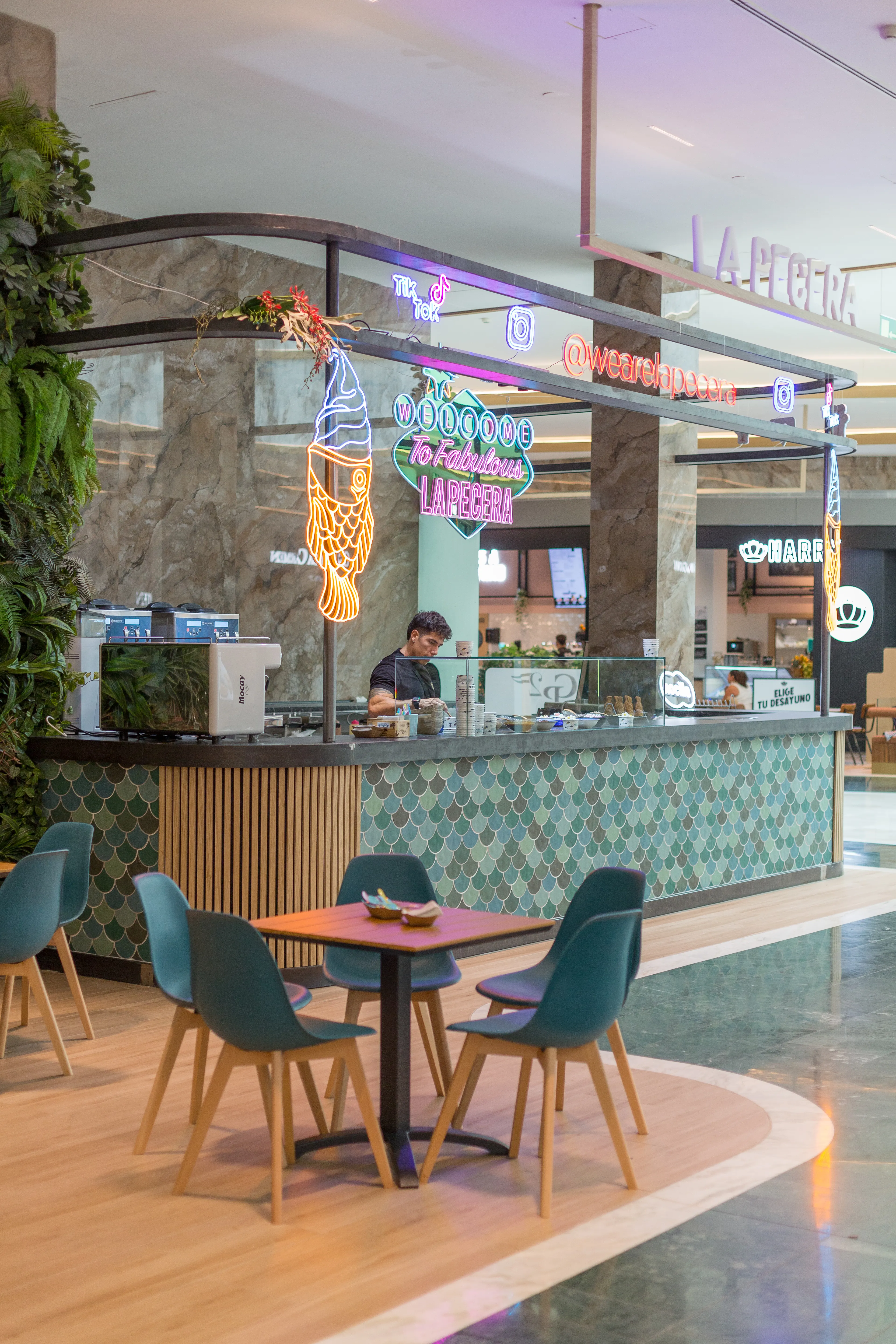 Mostrador con azulejos verdes, neones llamativos y espacio abierto en La Pecera Majadahonda, ideal para disfrutar de sus taiyakis con estilo.