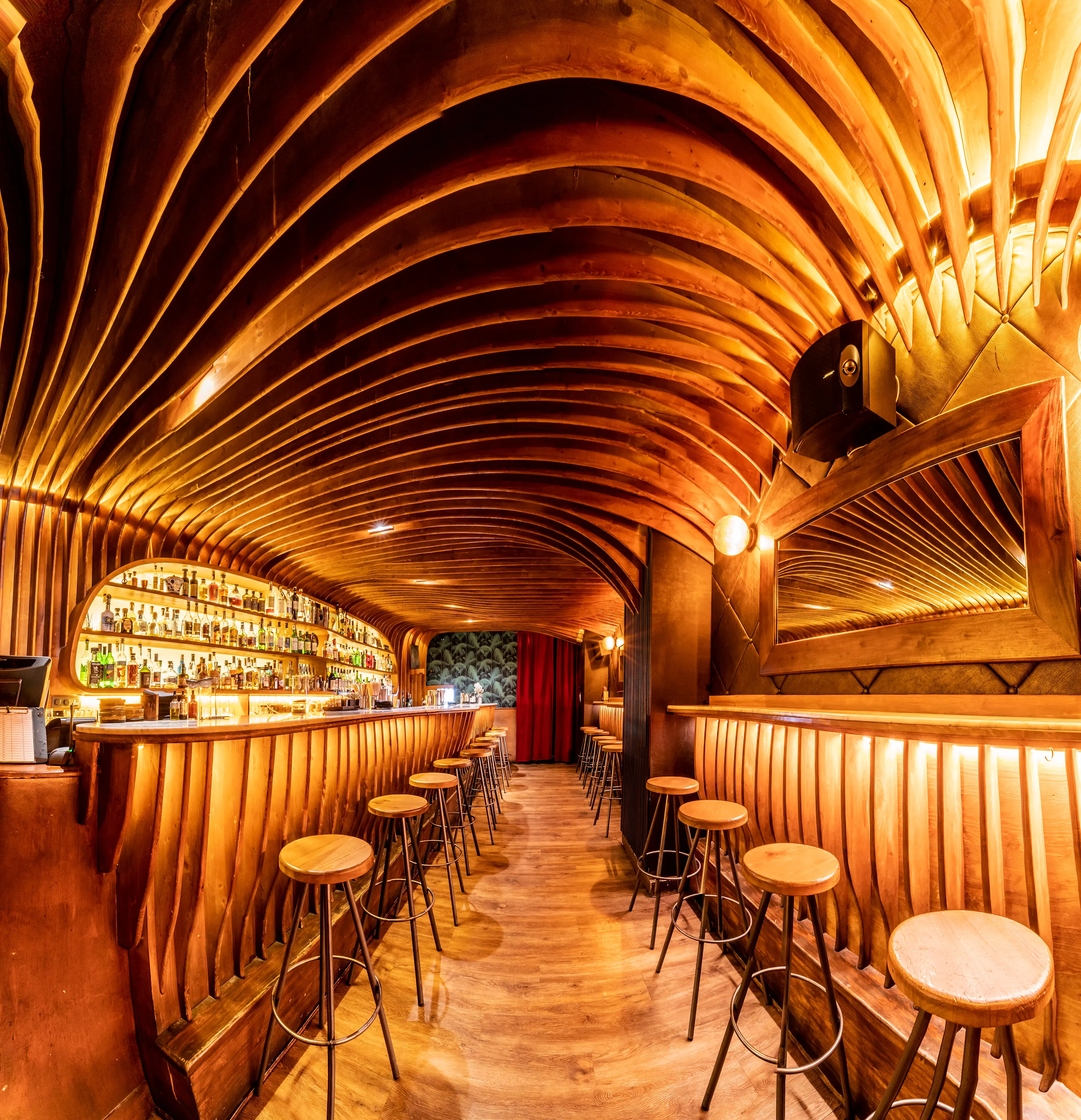 La imagen muestra un vaso que contiene un líquido naranja, un cóctel.Detrás del vaso hay un fondo oscuro con efectos de luz bokeh.