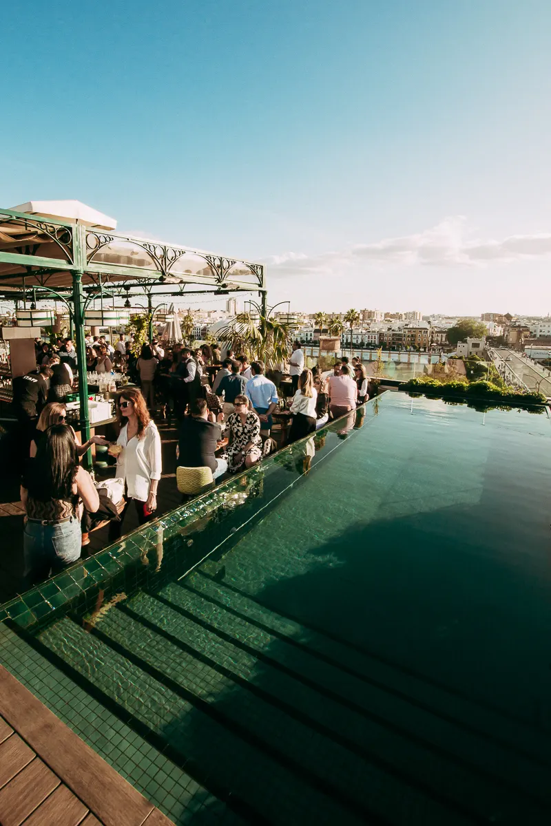 El bar de Ático brilla bajo un cielo de luces, rodeado de copas colgantes y una barra repleta, mientras la noche madrileña cobra vida entre conversaciones.