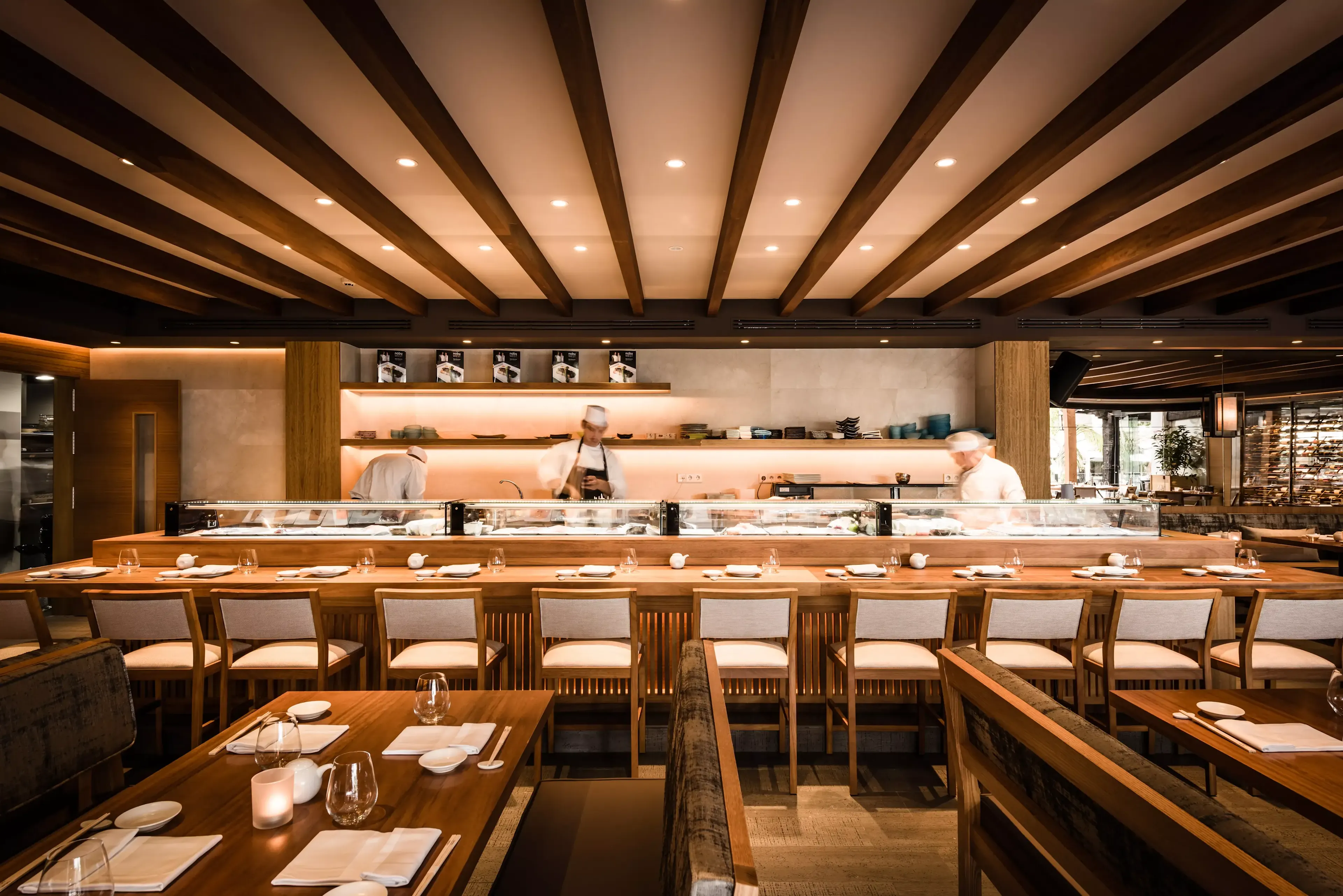 Nobu Marbella, restaurante moderno con barra de sushi y chefs en acción, ofreciendo una experiencia culinaria nipona de lujo.