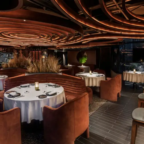 Interior de LEÑA, con diseño moderno, mesas elegantes y detalles de iluminación cálida que crean un ambiente sofisticado.