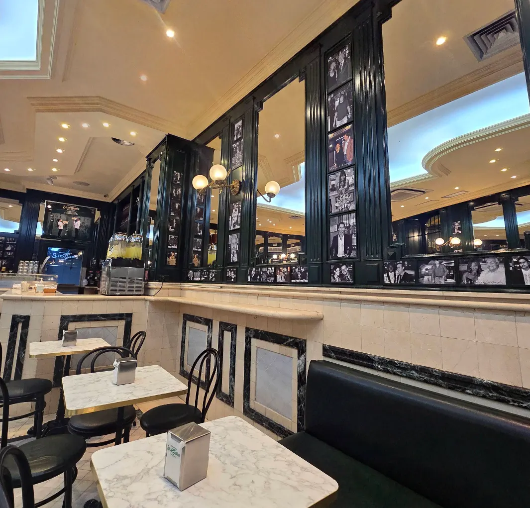 Mesas de mármol, espejos y fotos en blanco y negro decoran el interior clásico de San Ginés. Un café con historia y encanto madrileño.
