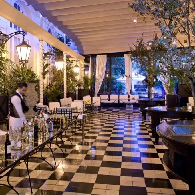 Rooftop Garden El Palace deslumbra con su elegante diseño, suelos ajedrezados y exuberante vegetación, creando un espacio sofisticado al aire libre.