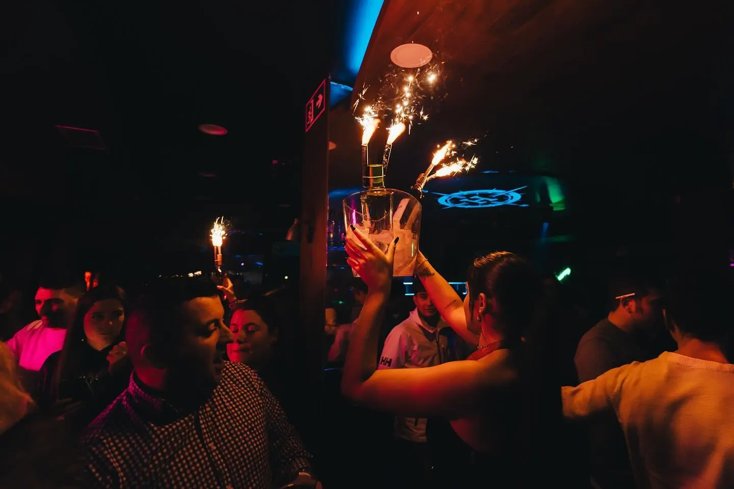 Celebración en Norte by Harbour con botellas y bengalas encendidas. Ambiente animado y festivo en una noche de fiesta.