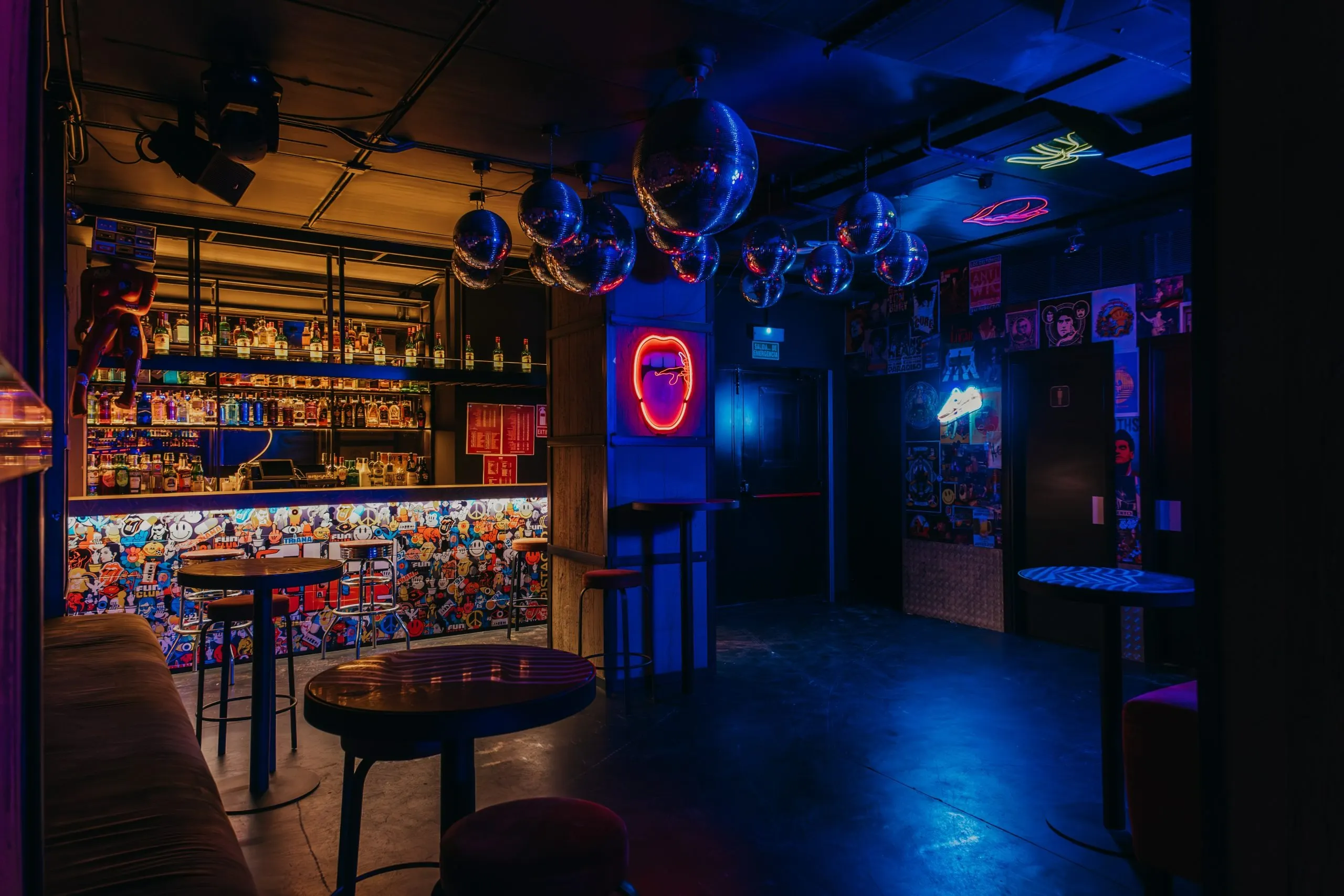 La imagen muestra un espacio interior de la Sala Fun  con una vibrante combinación de luces rojas y azules. En el centro, hay una estructura que parece ser una cabina de DJ con un ventilador que emite luz roja.