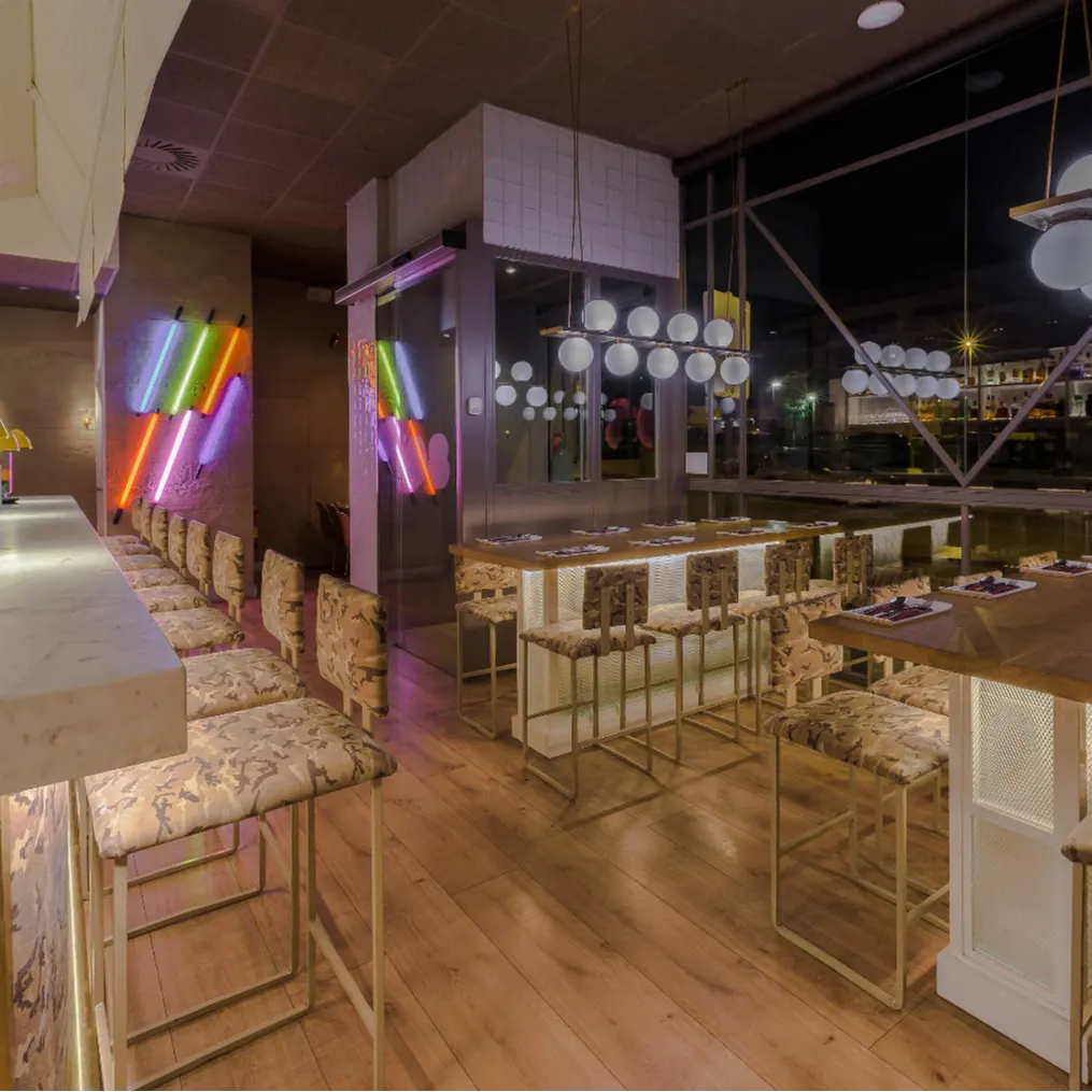 Interior de Ochenta Grados Las Tablas con barras iluminadas, neones de colores y sillas tapizadas en un ambiente moderno y lleno de energía.