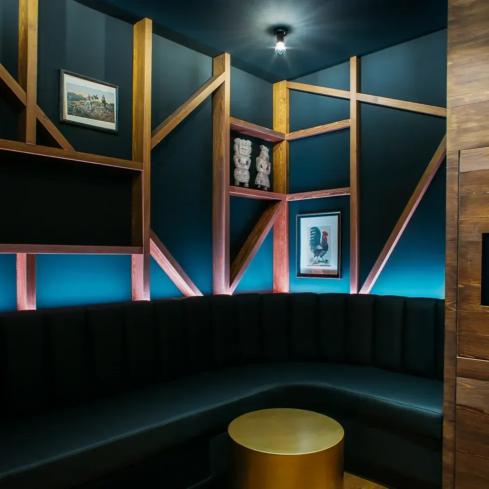 Un salón privado en BAM Karaoke Recoletos con un diseño elegante de tonos oscuros, sofás acolchados, decoraciones artísticas y luz ambiental.