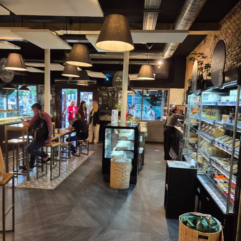 Interior moderno y funcional de Viena Capellanes Génova, con zona de refrigerados, mesas altas y luz cálida que invita a una pausa cómoda y rápida.