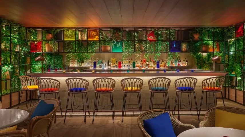 Oroya Madrid, un bar vibrante con taburetes coloridos, vegetación decorativa y una barra iluminada, perfecto para disfrutar de cócteles únicos.