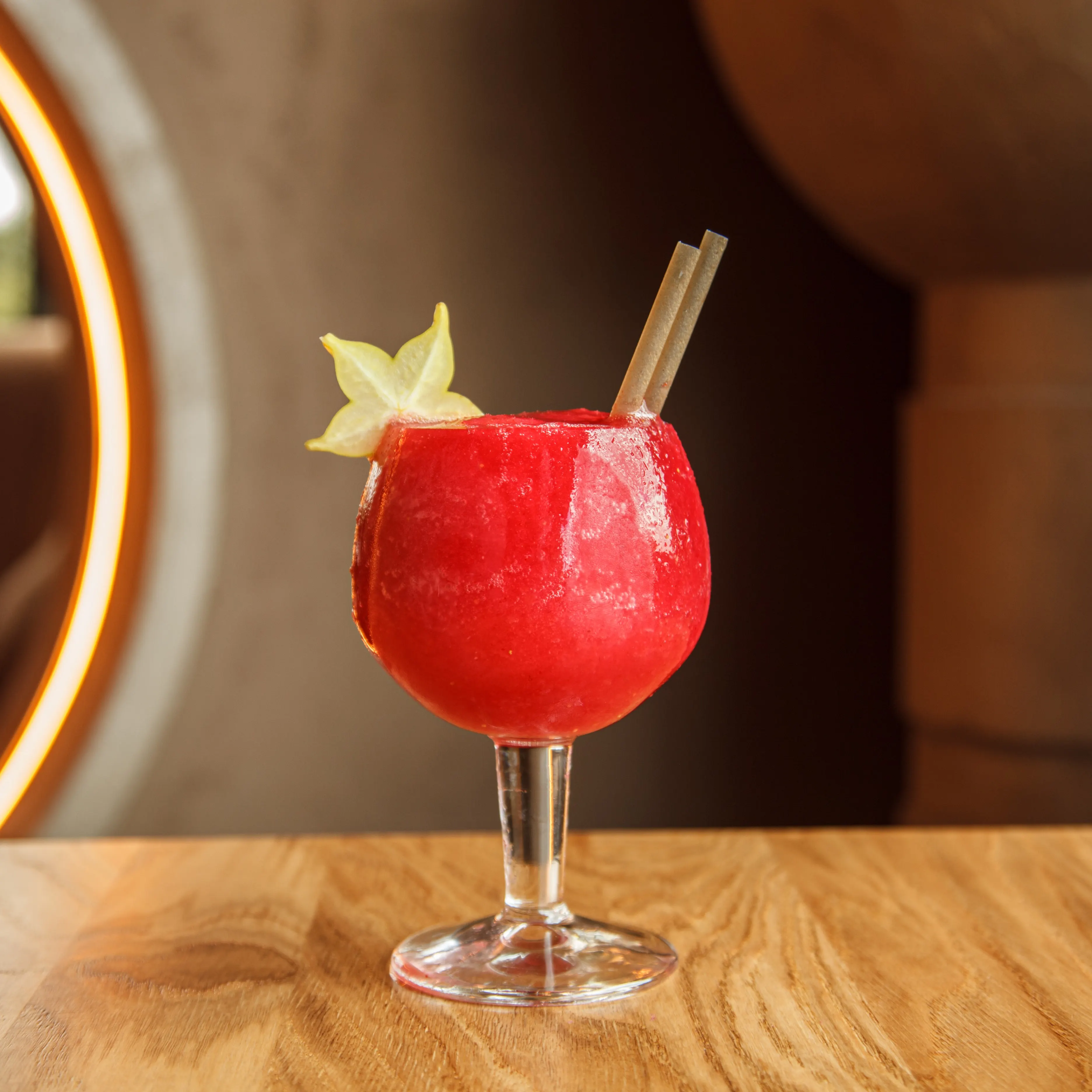 Cóctel granizado rojo servido en copa de balón en Ochenta Grados Las Tablas, con fruta en forma de estrella y fondo cálido y elegante.