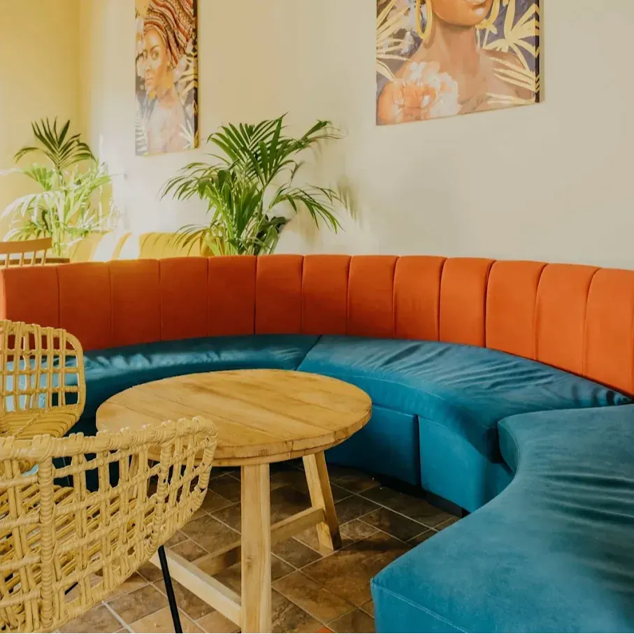 Botánico Café y Copas combina sofás curvos coloridos, sillas de mimbre y arte tropical, creando un ambiente fresco y acogedor.