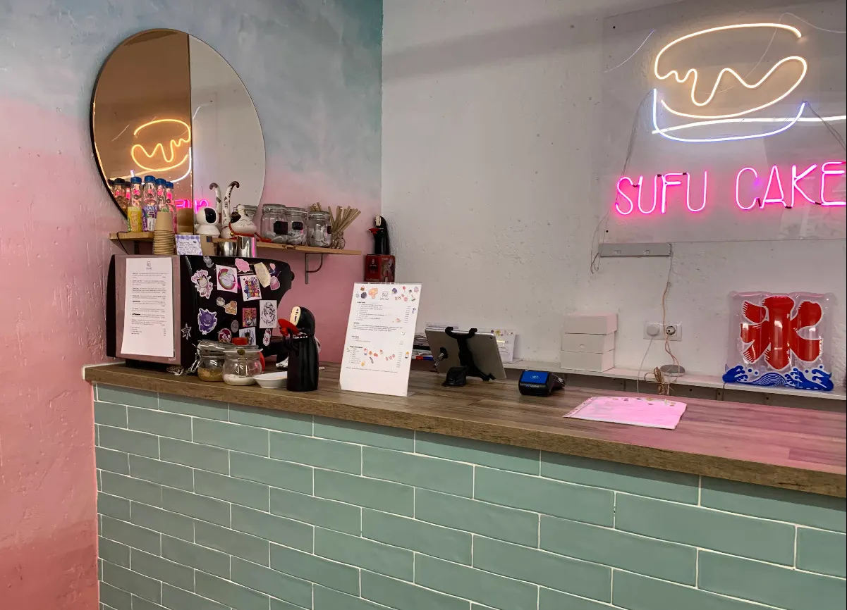 Mostrador de Sufu Cake con decoración japonesa, pared degradada y neón rosa con el logo del local.