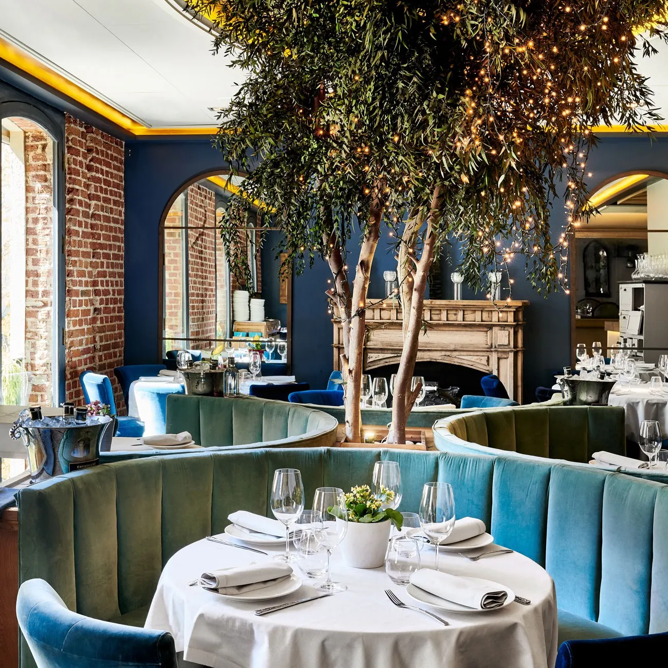 Ambiente sofisticado de Ten con Ten, con muros de ladrillo visto, asientos de terciopelo azul y detalles decorativos que irradian elegancia.
