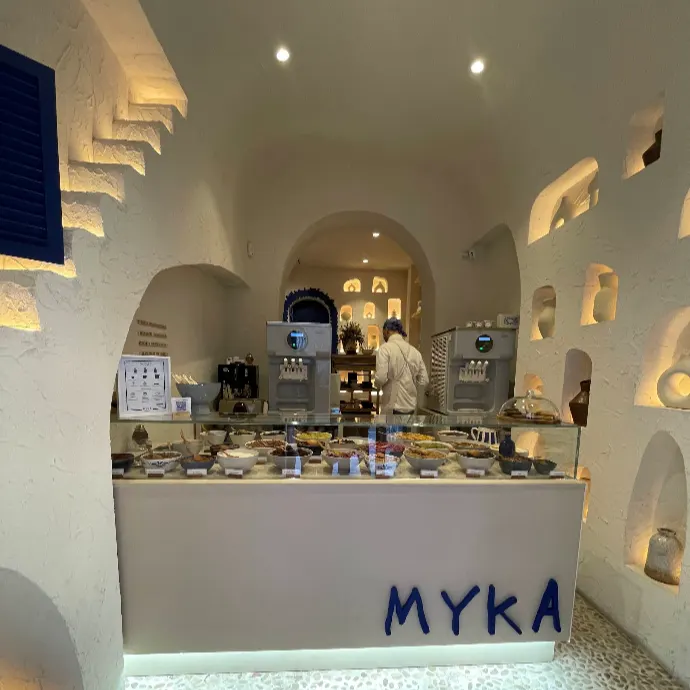 Interior de Myka San Lucas con mostrador de helados, paredes blancas abovedadas y hornacinas iluminadas.