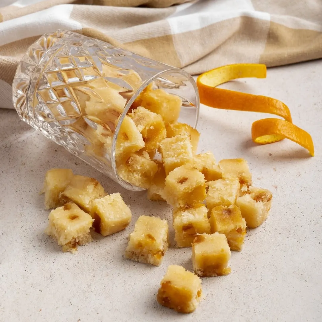 Dados de turrón blando con fruta confitada desbordando de un vaso de cristal tallado en Torrons Vicens.