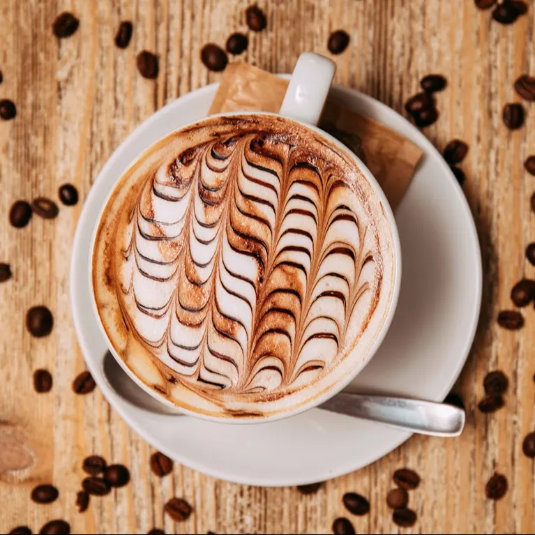 Capuccino con arte en la espuma servido en Julieta Coffee. Detalles que conquistan tanto por el sabor como por la vista.