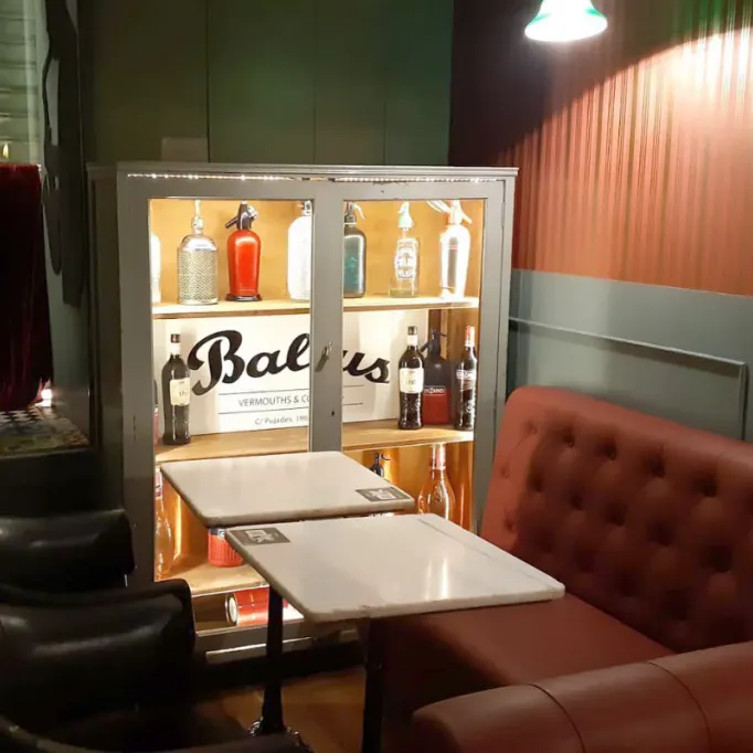 Balius Bar deslumbra con su vitrina iluminada llena de arte mixológico y un ambiente que mezcla elegancia retro y modernidad.