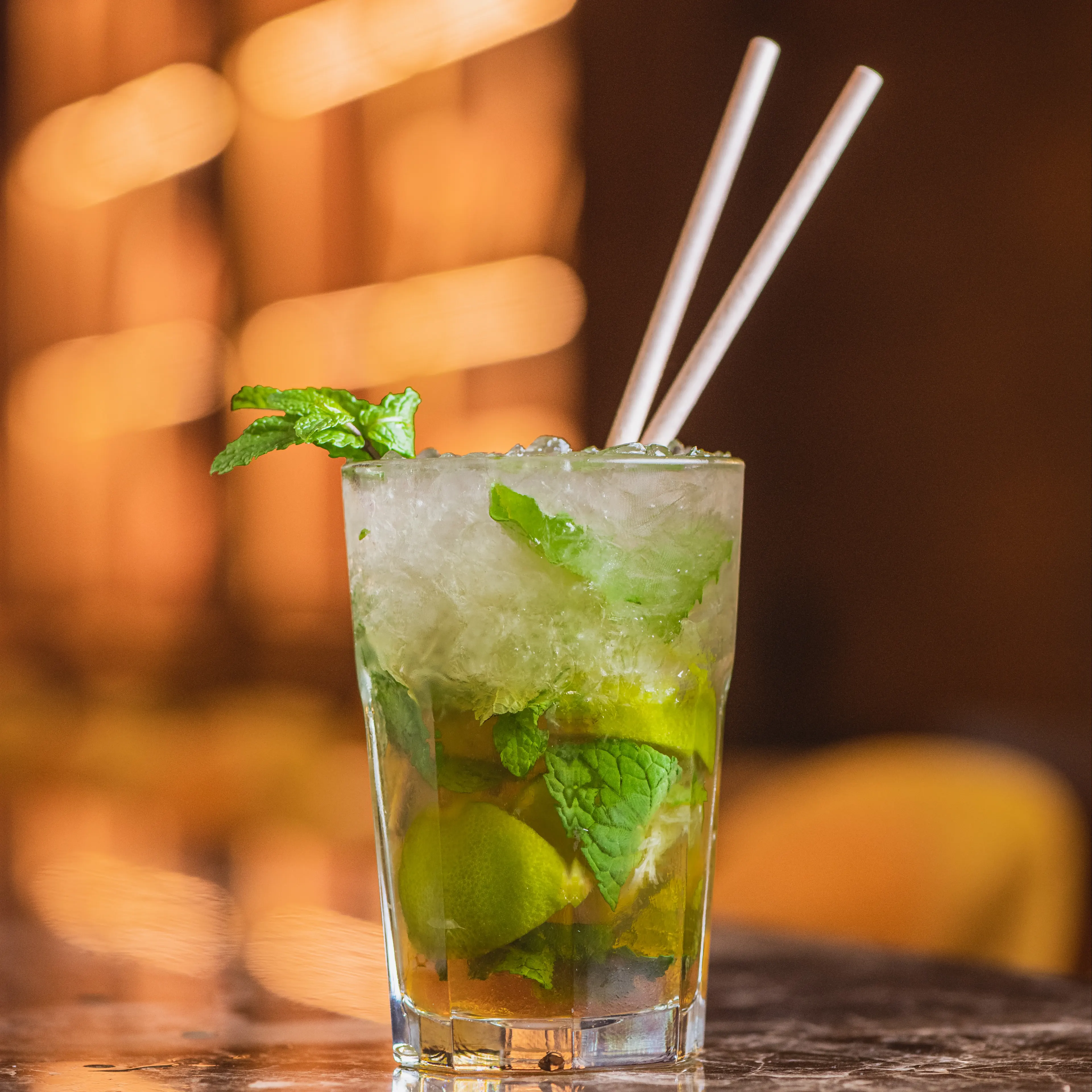 Mojito con lima y hierbabuena servido con hielo picado en Ochenta Grados Pozuelo, en una atmósfera elegante y llena de reflejos dorados.