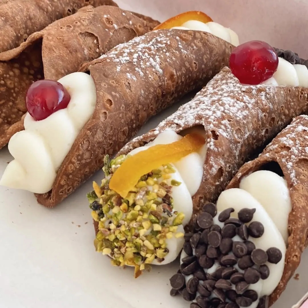 Copa de helado artesanal servida con fruta fresca, toppings coloridos y una galleta, presentada sobre bandeja plateada en Zùccaru.