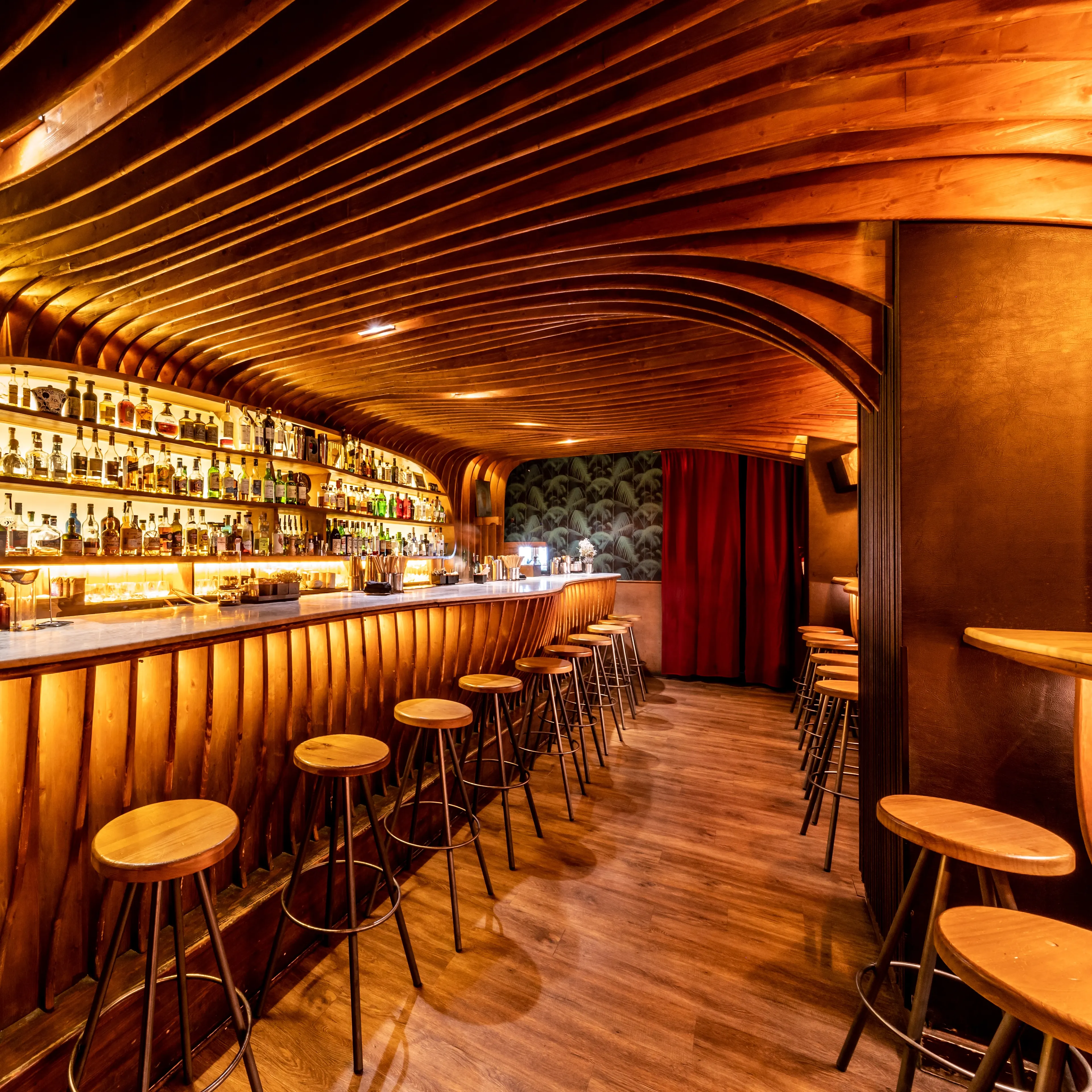 La foto muestra un primer plano de una superficie redonda de madera tallada con intrincados patrones y diseños. Sobre esta superficie, hay un pequeño cuenco con lo que parece ser una salsa, adornada con una hoja verde.