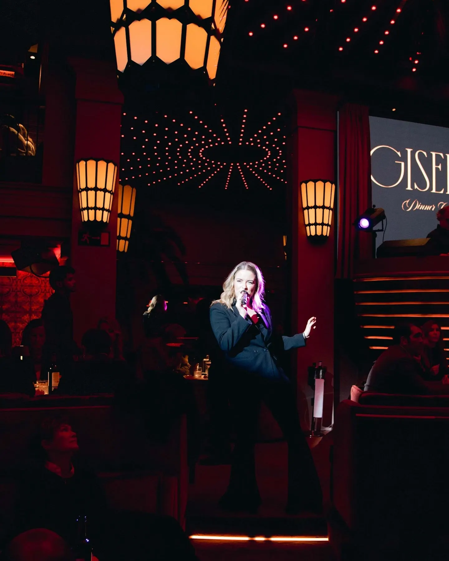 Una cantante en vivo bajo un juego de luces cálidas y modernas en Giselle Dinner Club, creando un ambiente íntimo y sofisticado.