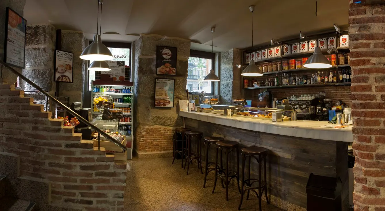 Interior de Viena Capellanes en Ruiz de Alarcón, con paredes de ladrillo visto, barra de mármol y ambiente cálido ideal para desayunar o tomar café.