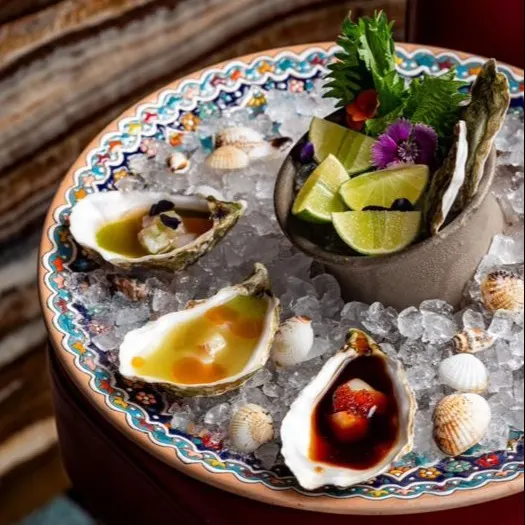 En Chanca Marbella, las ostras frescas sobre hielo se sirven con acompañamientos que resaltan la frescura del mar, decoradas con flores y lima.
