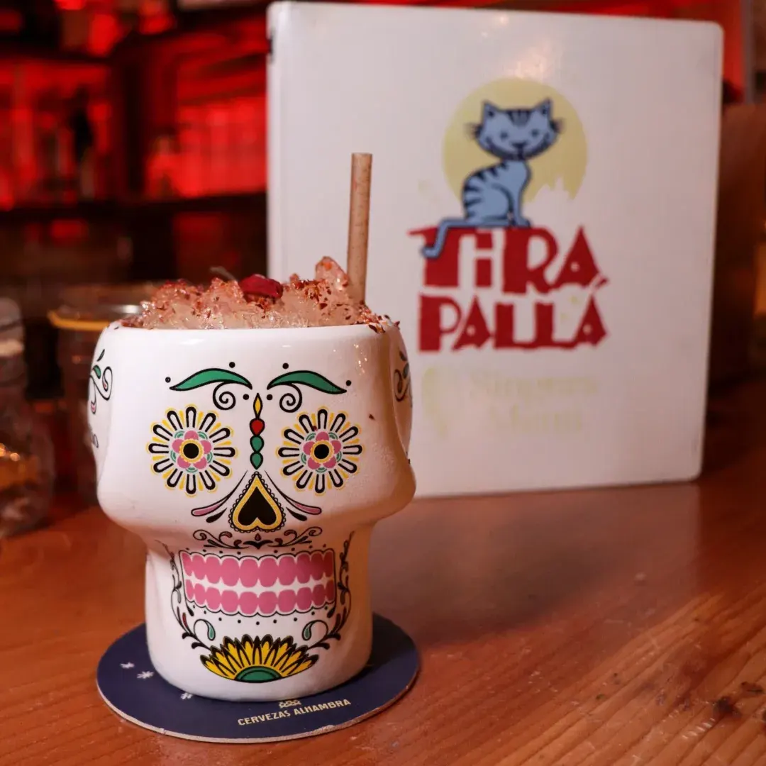 En Tira Palla los cócteles se sirven con arte y personalidad, como este trago en vaso de calavera rodeado de luz roja y sabor auténtico.