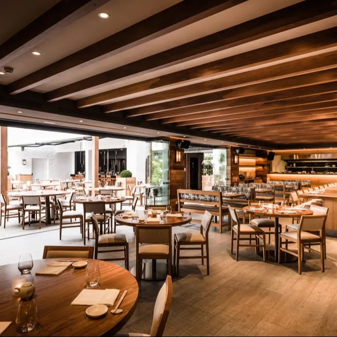 Interior de Nobu Marbella, con un diseño cálido de madera, mesas elegantemente dispuestas y una cocina abierta que resalta un ambiente sofisticado.