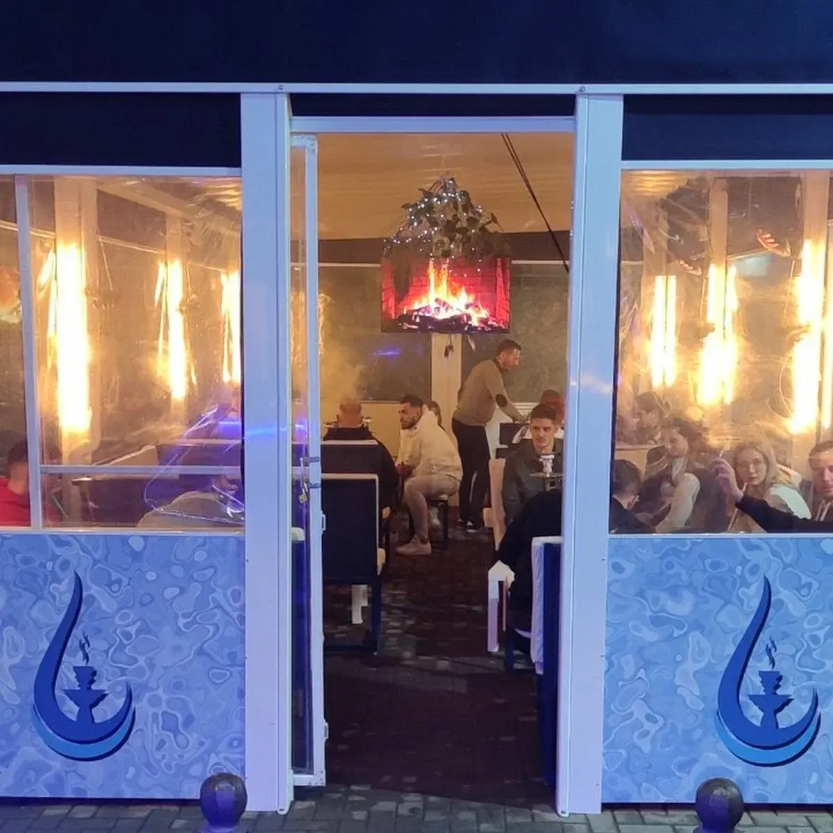 AQUA COCKTAILS BAR muestra una terraza iluminada con decoración minimalista, mesas llenas y un ambiente acogedor ideal para compartir.