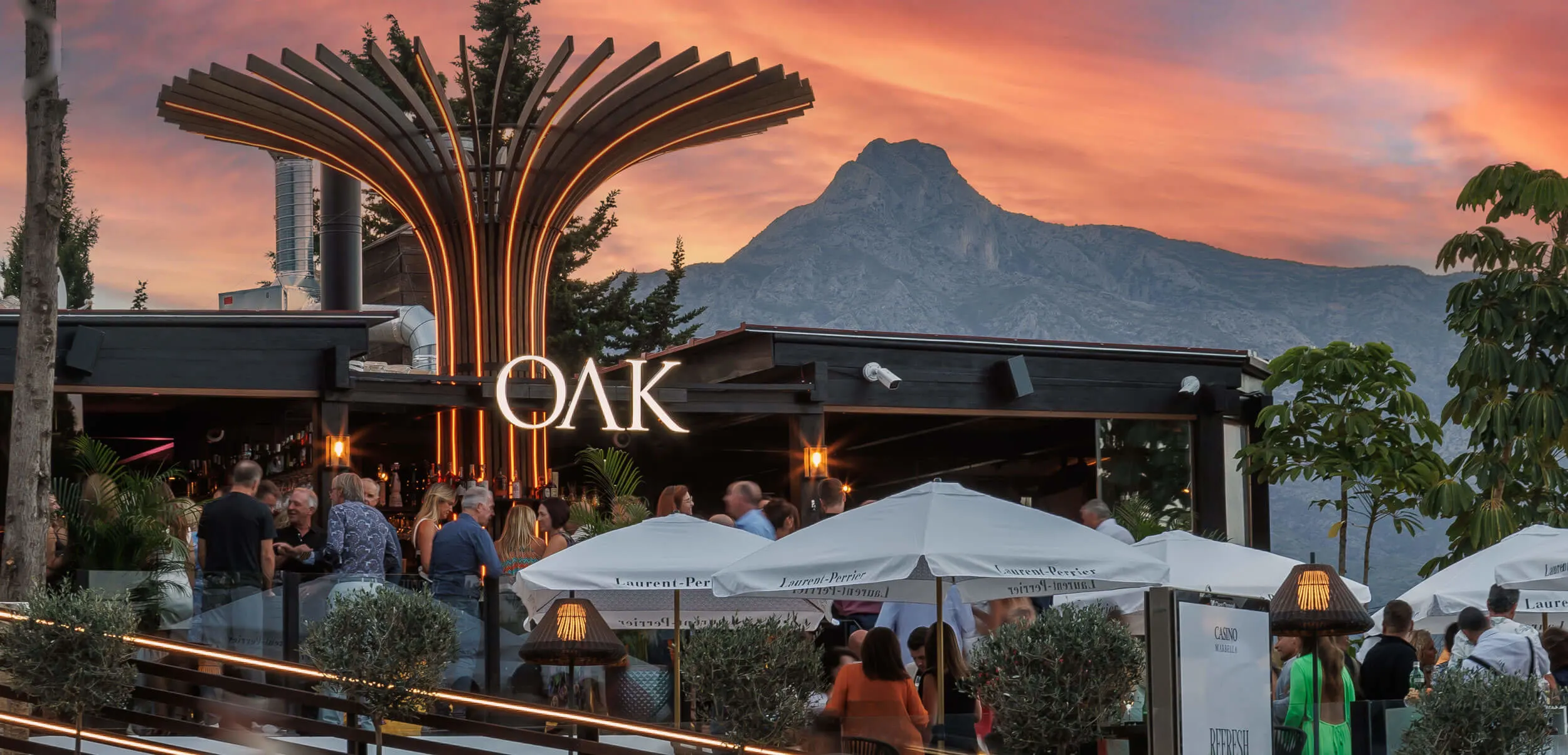 Oak Marbella, elegante terraza con vistas a la montaña y ambiente vibrante, donde disfrutar de cócteles y buena compañía en un entorno único.