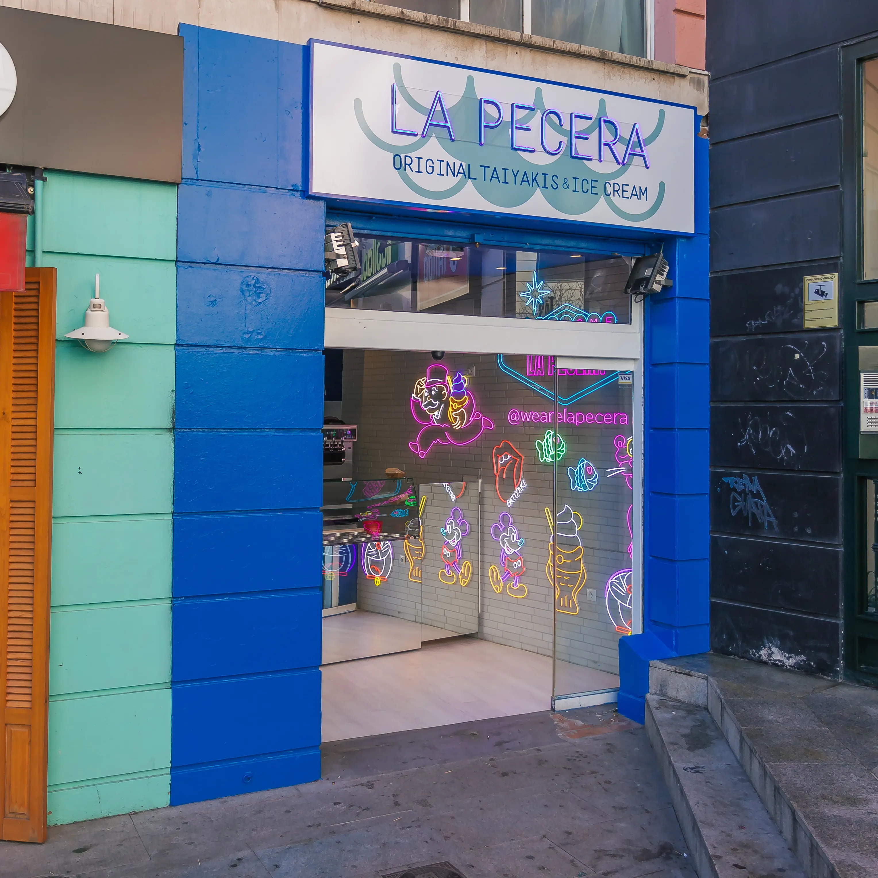Fachada colorida de La Pecera Rafaella Carrà con neones vibrantes, cristaleras abiertas y estética pop asiática desde el primer vistazo.