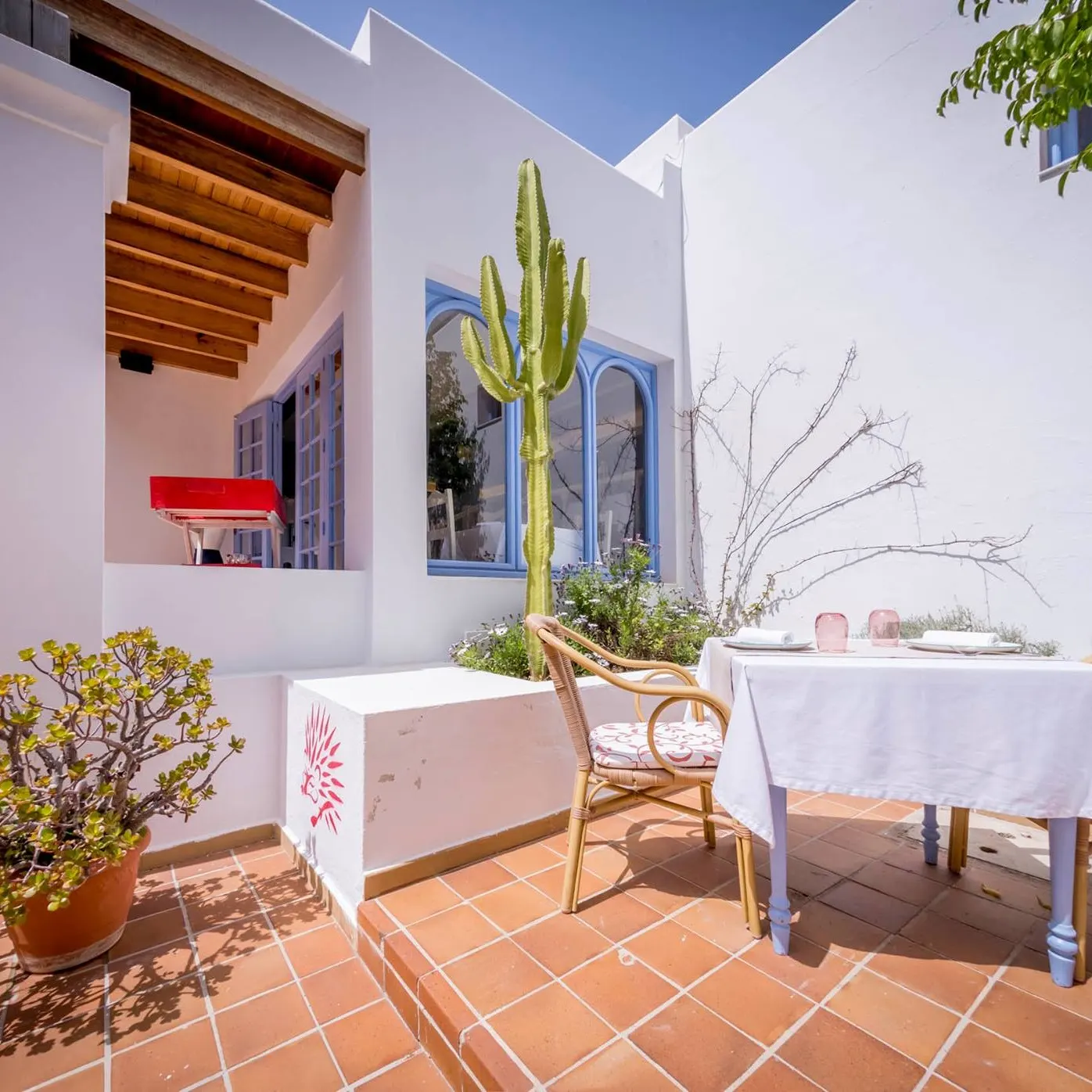 Terraza de Es Tragón, con arquitectura blanca de estilo mediterráneo, detalles en madera y un ambiente soleado rodeado de vegetación.