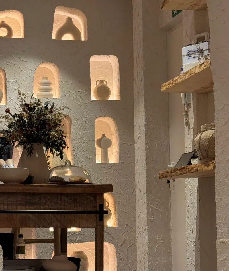 Detalle de Myka San Lucas con estanterías rústicas, cerámica artesanal y un ramo seco sobre mesa de madera.
