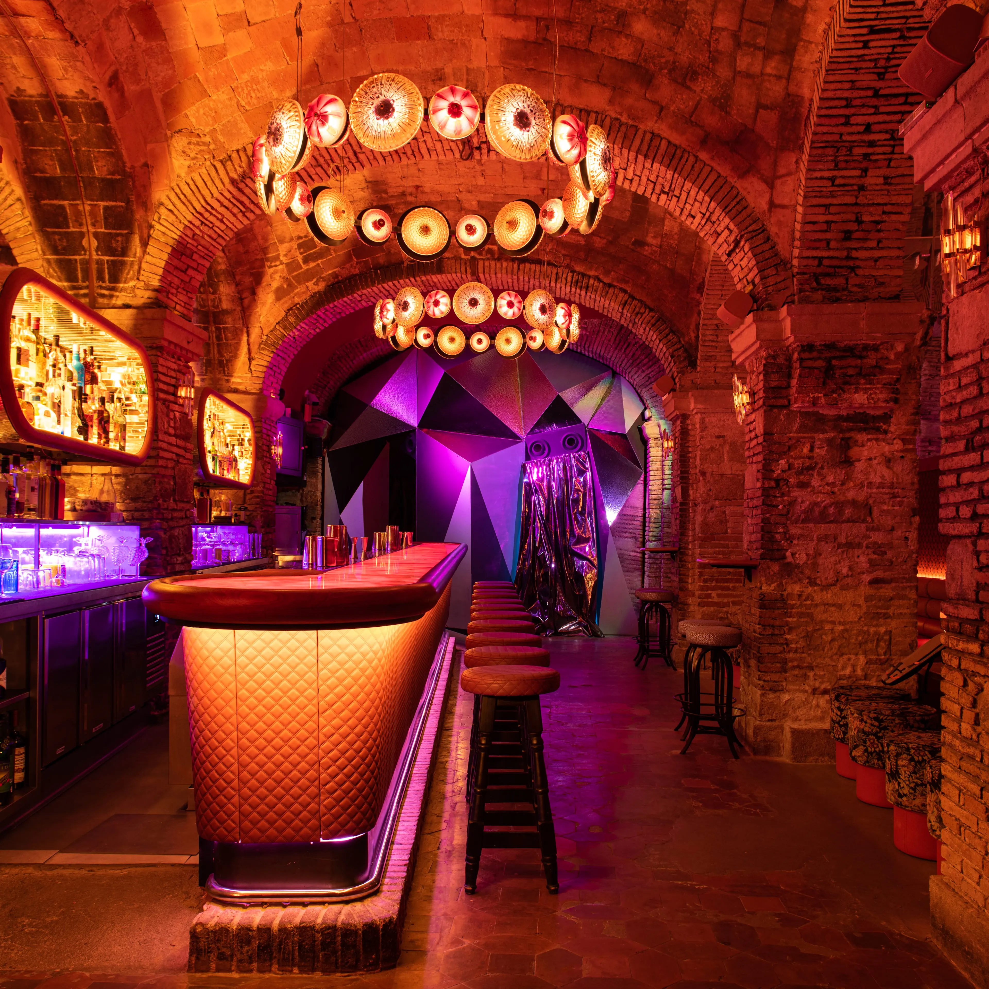 Monk combina arcos de ladrillo, luces cálidas y una barra futurista en un espacio íntimo, ideal para cócteles y noches exclusivas.