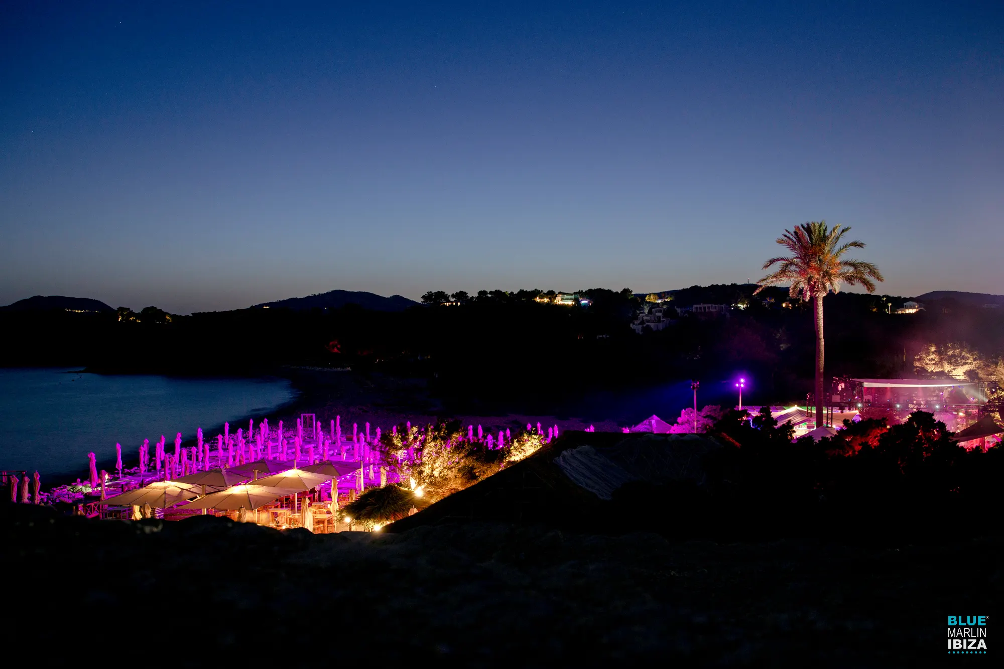 En Blue Marlin Ibiza, disfruta de la brisa marina y el ambiente vibrante de la playa mientras el lugar se ilumina al caer la noche.