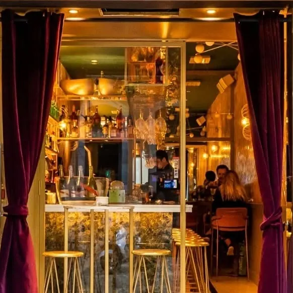 En La Perla, luces cálidas, cortinas aterciopeladas y un bar bien surtido crean una atmósfera acogedora y elegante para disfrutar.