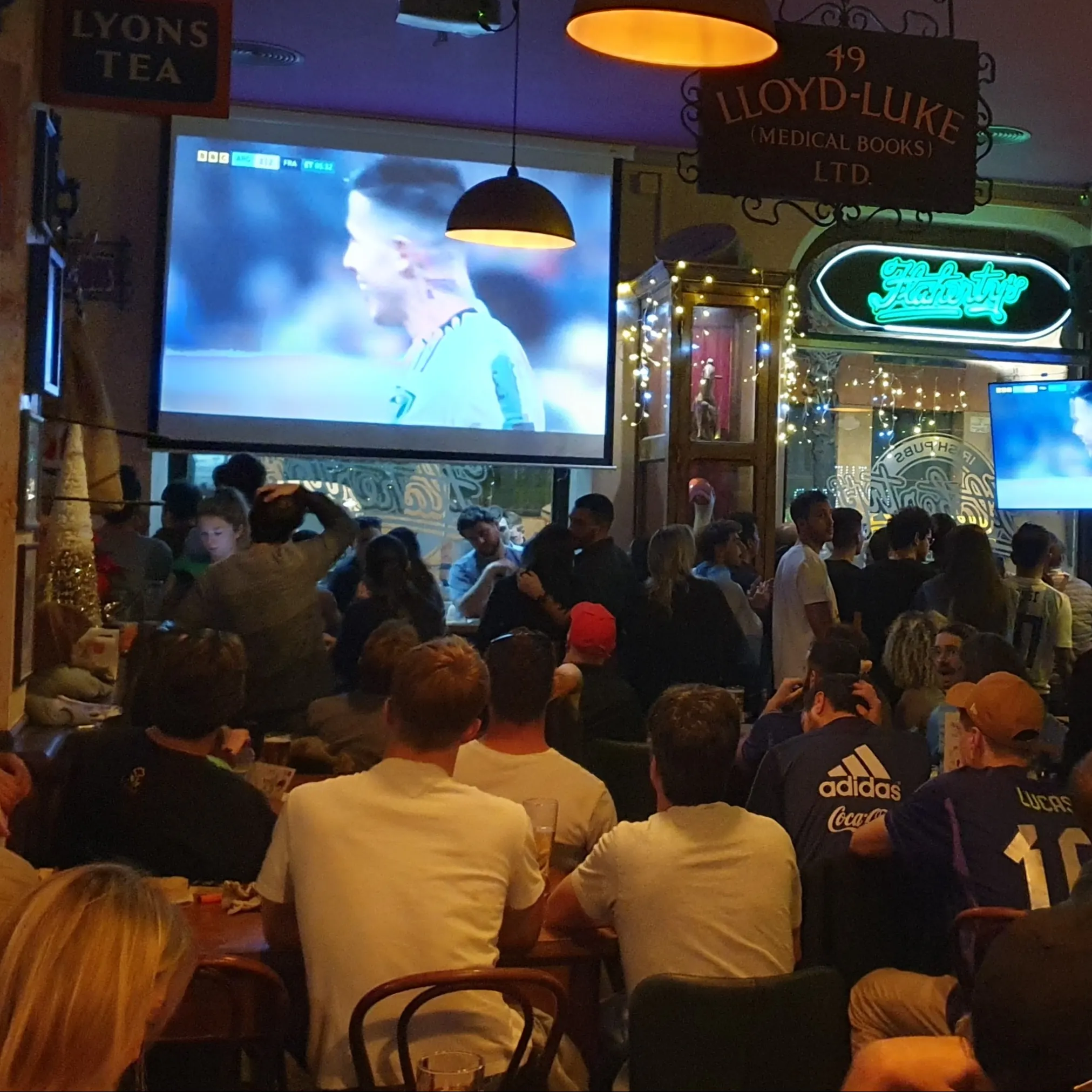 La imagen muestra el interior de Flaherty´s, con los clientes enfocados en una pantalla de televisión transmitiendo un evento deportivo.