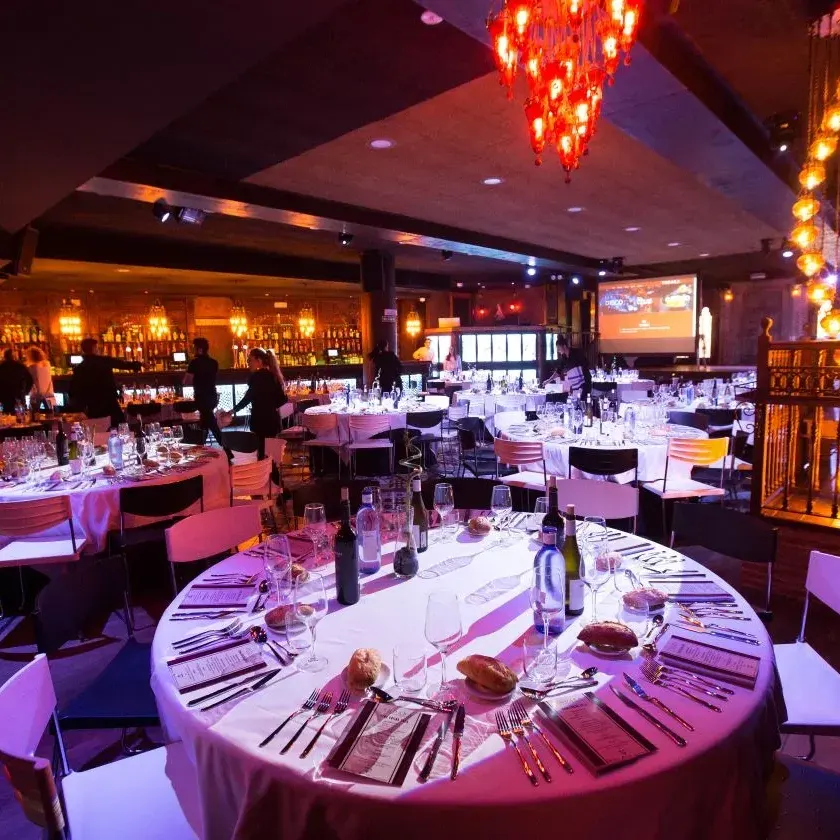 Indara, un elegante salón para eventos, mesas impecablemente vestidas, candelabros vibrantes y un ambiente cálido y sofisticado.