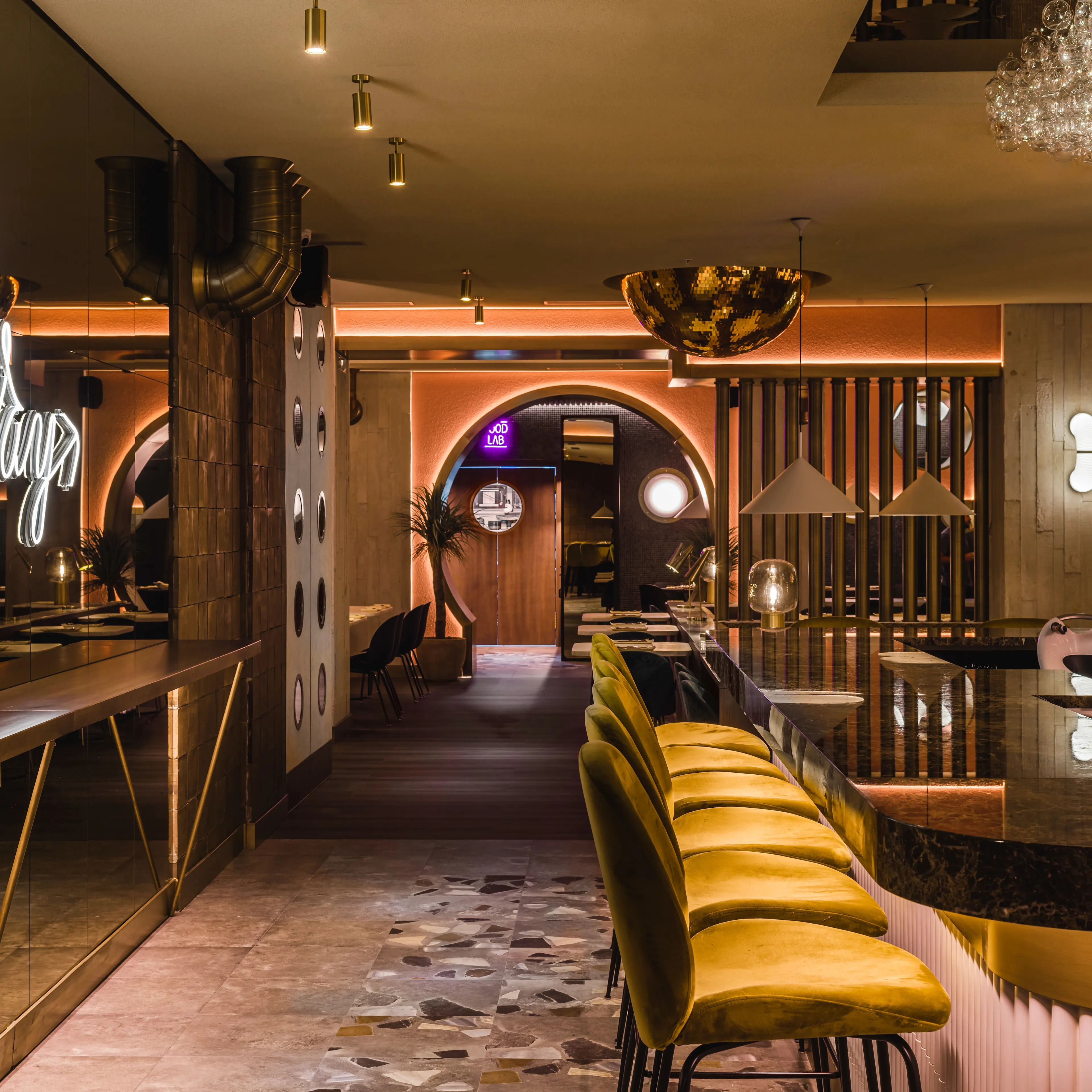 Interior sofisticado de 80 Grados Castellana, con barra de mármol, sillas doradas y una iluminación envolvente que crea un ambiente moderno y elegante.