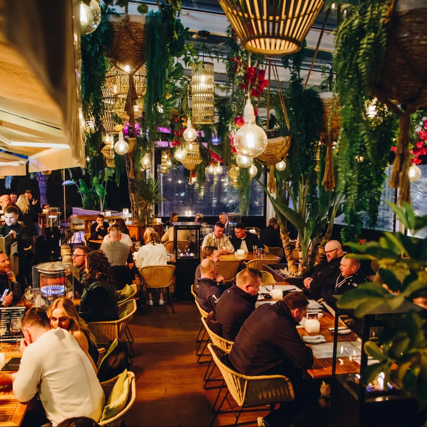 Terraza de La Sala Banús, con ambiente animado, decoración tropical y cálida iluminación para disfrutar de cenas especiales.