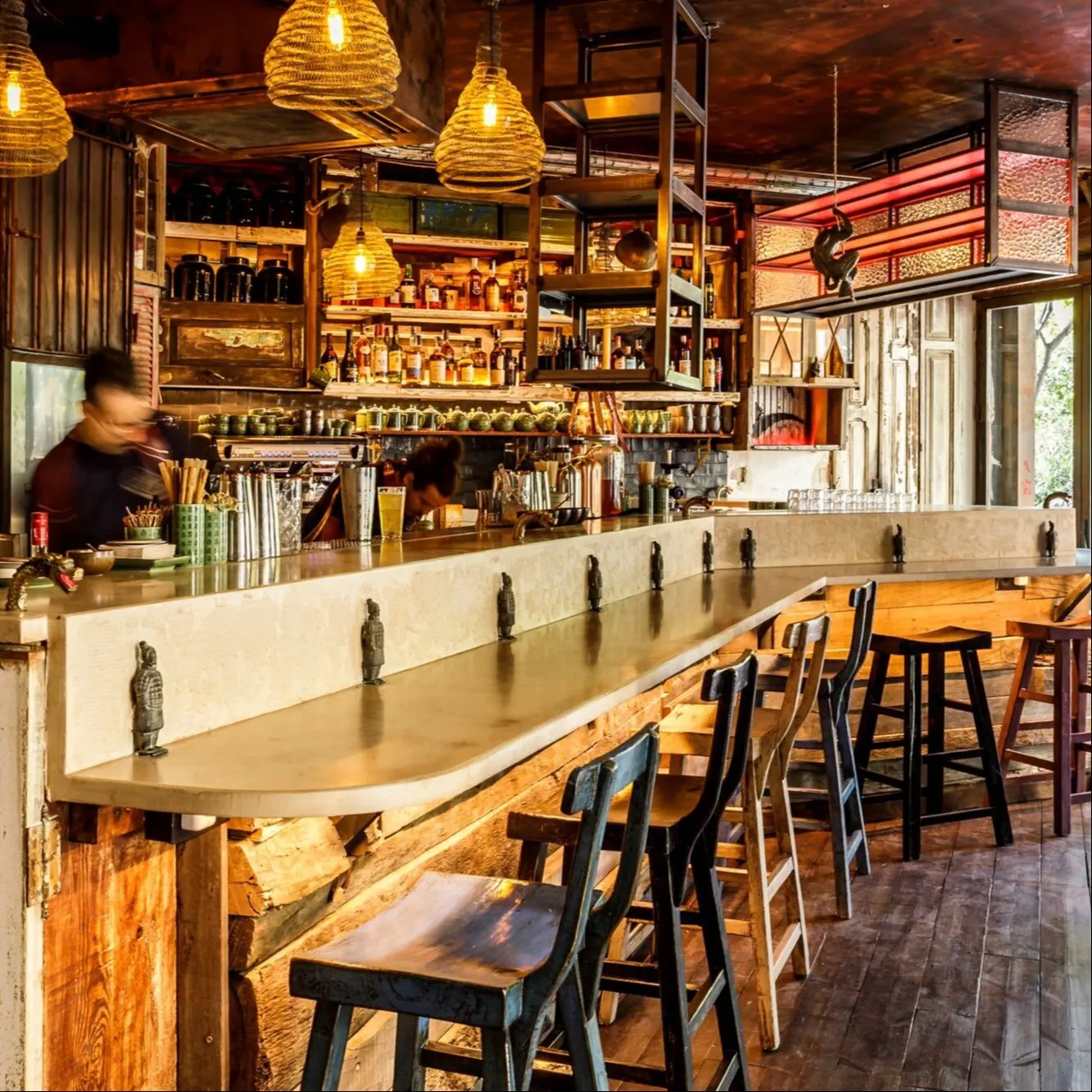 Barra de madera con taburetes altos y lámparas colgantes de cuerda en un ambiente cálido y rústico en Boa Bao.