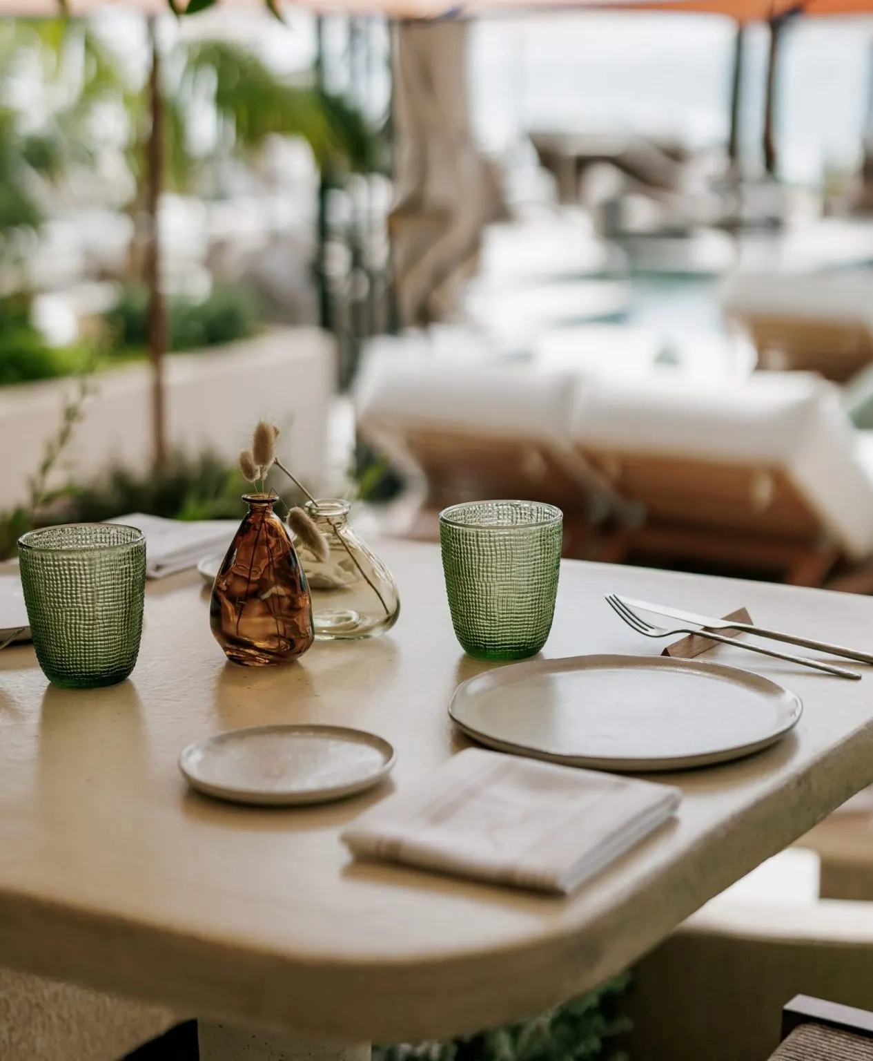 Sublim Beach combina elegancia y frescura con mesas decoradas de manera minimalista junto a cómodas tumbonas, ambiente relajado frente al mar.