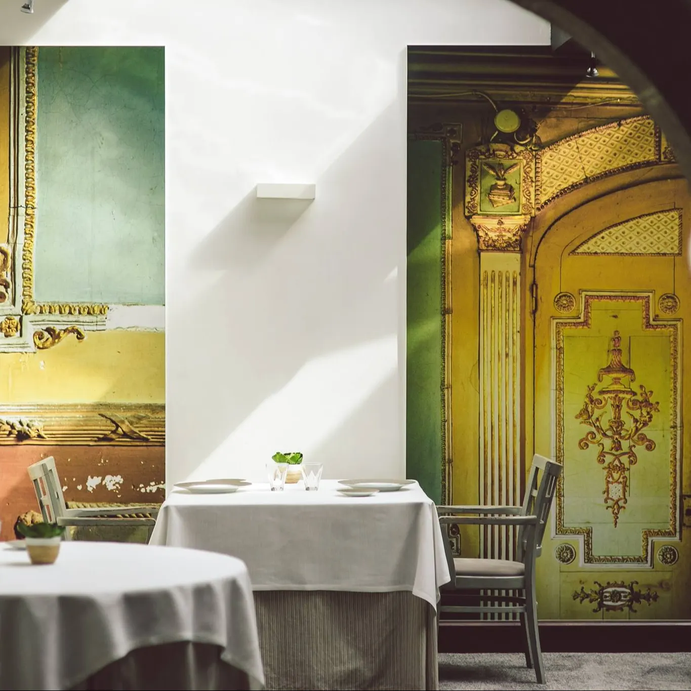Encanto clásico en Cenador de Amós, una sala luminosa con murales neoclásicos y mesas elegantemente dispuestas para una experiencia única.