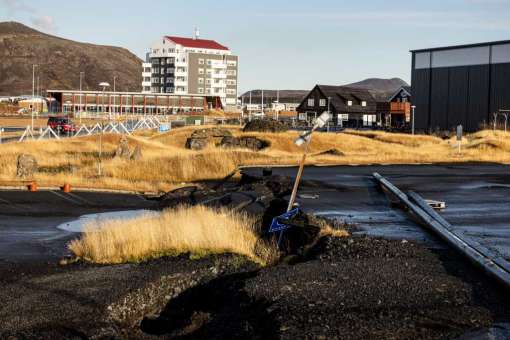 A cracked road and tilted street sign in Grindavík