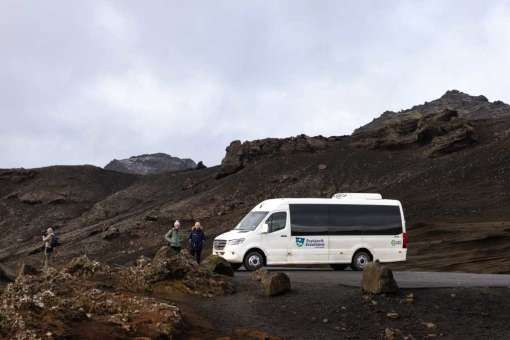 A tour bus is parked on a volcanic landscape near Grindavík