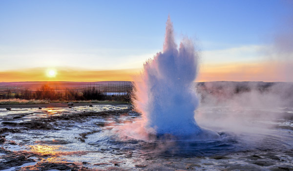 Strokkur geyser erupts during sunset