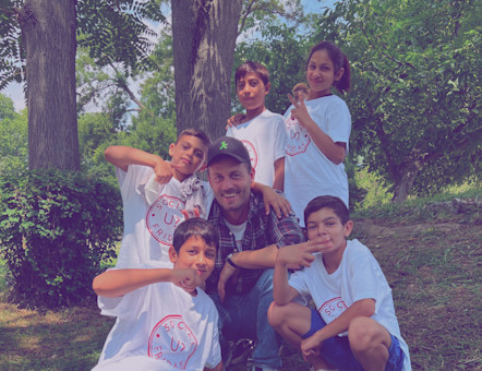 Ein Mann, und ein paar Kinder posieren für das Foto, vor einem Baum