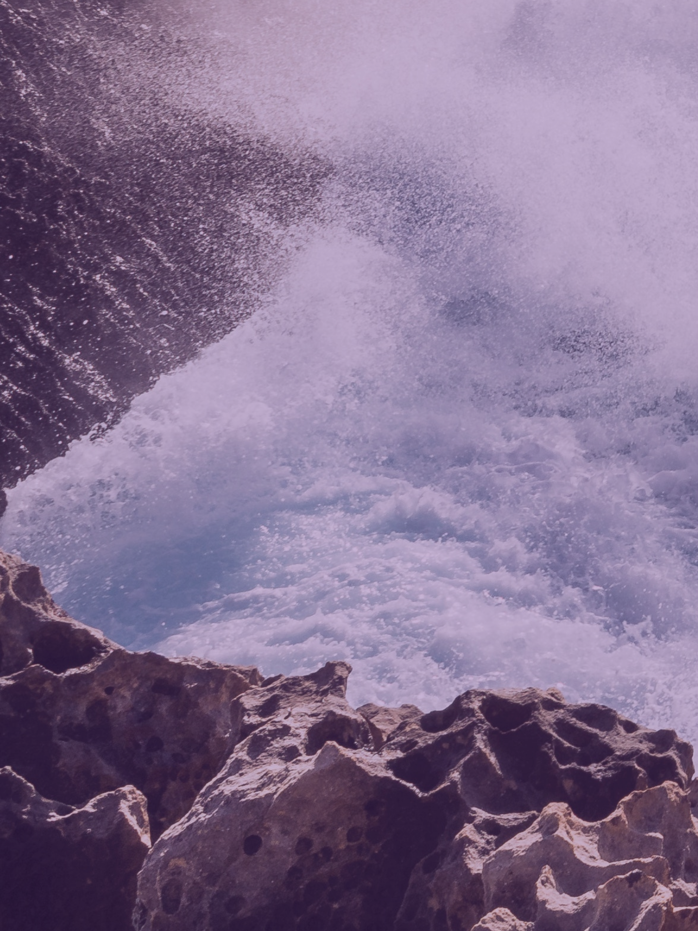A wave crushing rocks large image 